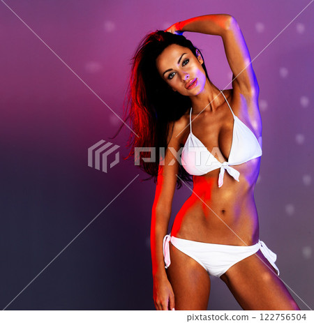 Sexy, fitness and body beauty model in a bikini showing skin and stomach with mockup space. Portrait of a healthy, young and sensual woman with confidence, mock up purple background and disco light 122756504