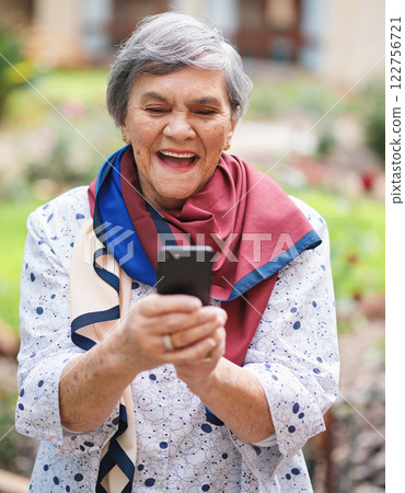 Senior woman, smile and smartphone for communication, outdoors and online conversation in garden. Elderly person, social media and laughing outside for funny joke on technology, retirement and typing 122756721