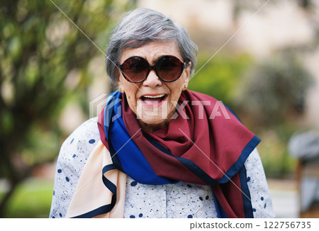 Laughing, senior woman and garden or park with smile from walk, spring and nature. Elderly female person, happy and outdoor of retirement home or on vacation with travel in London with sunglasses 122756735