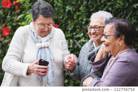 Elderly women, friends and earphones with phone, listen or happy with sunglasses in backyard for music. People, retirement and smartphone for audio streaming subscription, podcast or group with radio Elderly women, friends and earphones with phone, listen or happy with sunglasses in backyard for music. People, retirement and smartphone for audio streaming subscription, podcast or group with radio 122756750