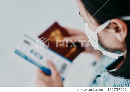 A woman traveling during the covid pandemic holding her passport and flight ticket at the airport. A tourist leaving the country due to the ease of travel restrictions during the coronavirus pandemic 122757012