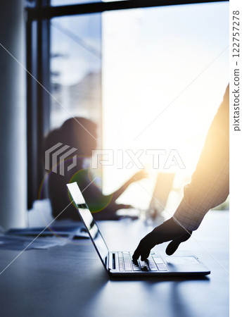 Silhouette of the hand of a businessman working on a laptop in an office with sunlight and a blurred shadow of a woman in the background with bokeh. Outline of a male brainstorming in the office. 122757278