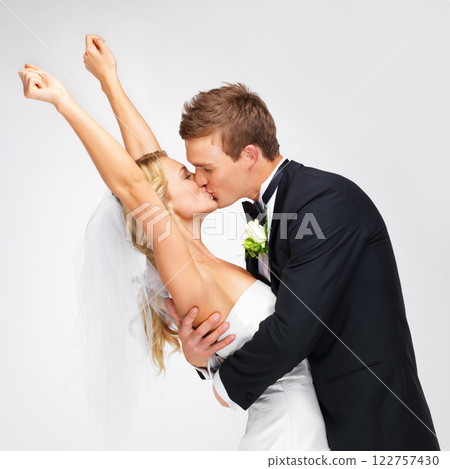 Love, wedding and happy couple kiss at their marriage reception on a white studio background. Man, woman or bride and groom in celebration of their commitment, union or luxury romantic event 122757430