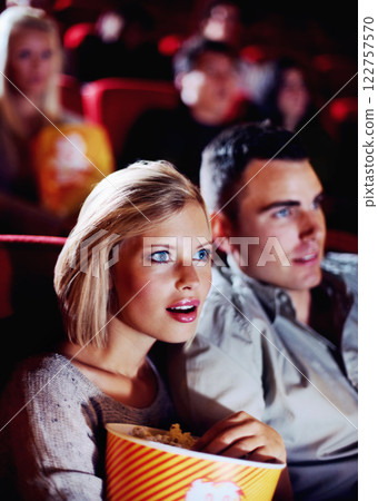 Film, cinema and couple love popcorn at the movie theatre at night in a dark room for horror, action and scary entertainment. People, man and young woman watching romantic comedy together on date 122757570