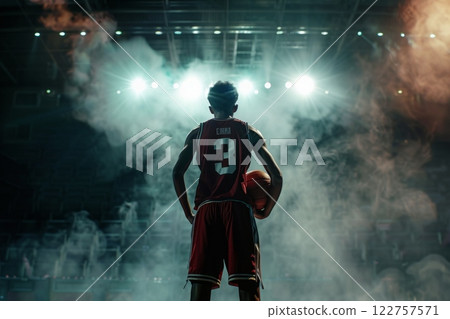 A basketball player strikes an intense pose on court amid smoke effects, exhibiting strength and intensity 122757571