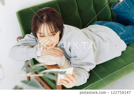 Woman using smartphone on sofa 122758147