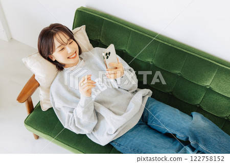Woman using smartphone on sofa Woman using smartphone on sofa 122758152