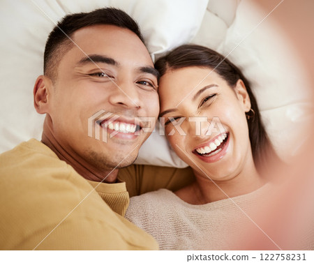 A happy and in love couple taking a selfie while smiling, laughing and looking cute portrait. Romantic, fun and sweet boyfriend and girlfriend bonding, relaxing and enjoying quality together in bed 122758231