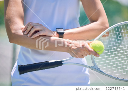 Sports, arm pain and tennis player with a racket and ball standing on a court during for a match. Closeup of a health, strong and professional athlete with equipment touching a medical elbow injury. 122758341
