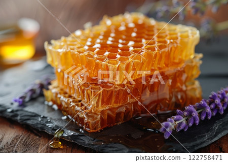 A golden honeycomb delight piece, with honey dripping from its edges, placed elegantly on a dark slate plate. 122758471