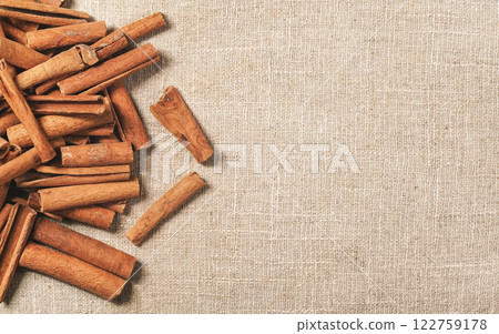 Top down view - Heap of cinnamon bark sticks on linen tablecloth, space for text on right side Top down view - Heap of cinnamon bark sticks on linen tablecloth, space for text on right side 122759178