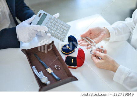 A middle-aged woman and a specialist buyer assessing precious metals 122759849