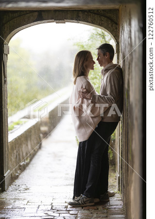 Romantic couple embracing in tunnel during rain shower 122760512