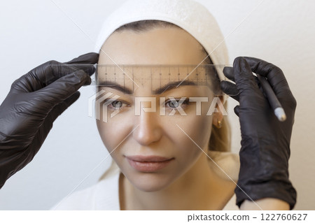 Eyebrow tattooing .Permanent eyebrow makeup master applies the contour with ruler on the client's eyebrow 122760627