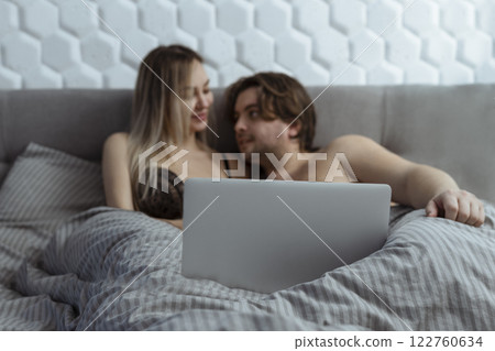 Couple watching porn movie over laptop in bedroom  122760634