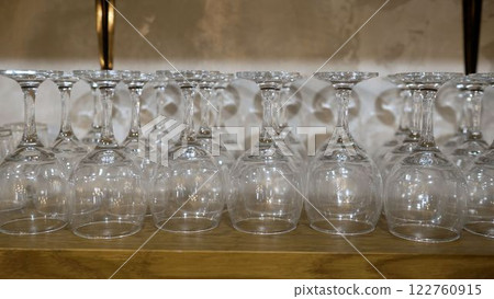 Empty wine glasses drying upside down on wooden shelf 122760915
