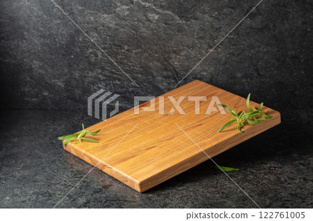 Empty cutting board with rosemary on a black stone background. Empty cutting board with rosemary on a black stone background. 122761005