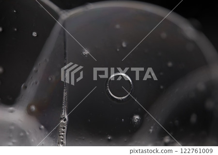 Transparent liquid surface, bubbles of thick liquid, silver reflection on dark background, gray colours, dark abstraction 122761009