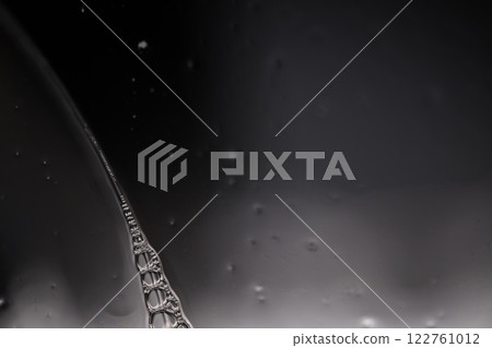 Transparent liquid surface, bubbles of thick liquid, silver reflection on dark background, gray colours, dark abstraction Transparent liquid surface, bubbles of thick liquid, silver reflection on dark background, gray colours, dark abstraction 122761012
