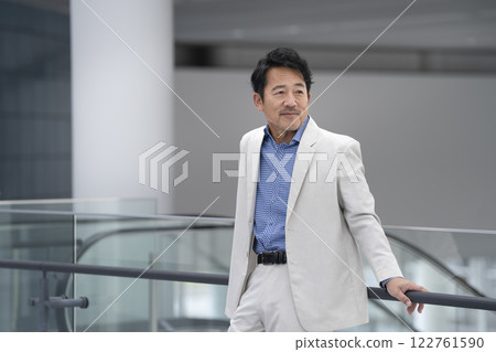 一位 50 多歲、身穿白色夾克的男子麵帶微笑 122761590
