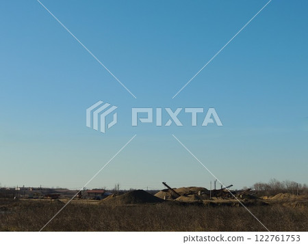 mining and crushing of natural stone on open flat terrain, piles of crushed rock at the site of soil extraction, machinery and piles of gravel and screenings view from afar mining and crushing of natural stone on open flat terrain, piles of crushed rock at the site of soil extraction, machinery and piles of gravel and screenings view from afar 122761753