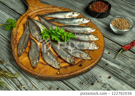 A bountiful layout features freshly caught fish on a rustic cutting board, surrounded by vibrant herbs and colorful spices, creating a lively atmosphere perfect for a culinary adventure 122762036
