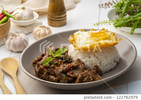 Stir fried sliced Beef with Holy Basil and Cooked Rice topped with fried egg in white plate.Thai spicy food(Pad Kra pao) Stir fried sliced Beef with Holy Basil and Cooked Rice topped with fried egg in white plate.Thai spicy food(Pad Kra pao) 122762979