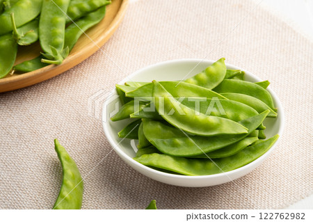 Fresh raw flat green peas or snow peas in white plate. Fresh raw flat green peas or snow peas in white plate. 122762982