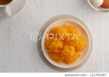 Crispy Sweet egg floss or Golden Thread Egg,Shredded Egg Yolk Tart in white plate.Top view. 122762987