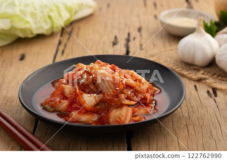 Close up Napa cabbage kimchi topped with white sesame seed in black plate,Korean fermented side dish food. Close up Napa cabbage kimchi topped with white sesame seed in black plate,Korean fermented side dish food. 122762990