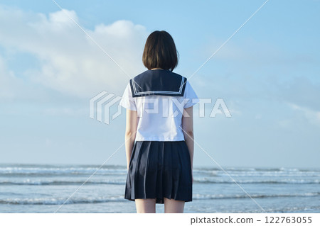 A high school girl standing with the blue sky and sea in the background A high school girl standing with the blue sky and sea in the background 122763055