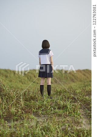 Back view of a high school girl standing on a grassland 122763081