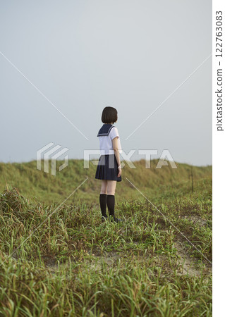 Back view of a high school girl standing on a grassland 122763083