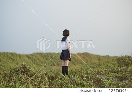 Back view of a high school girl standing on a grassland 122763084