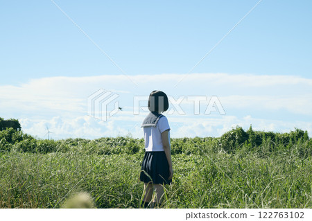 A high school girl standing on a grassland under a blue sky 122763102