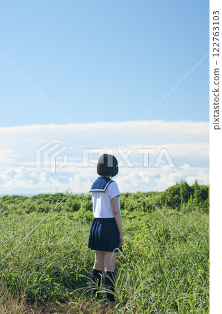 一名高中女生站在藍天下的草地上 一名高中女生站在藍天下的草地上 122763103