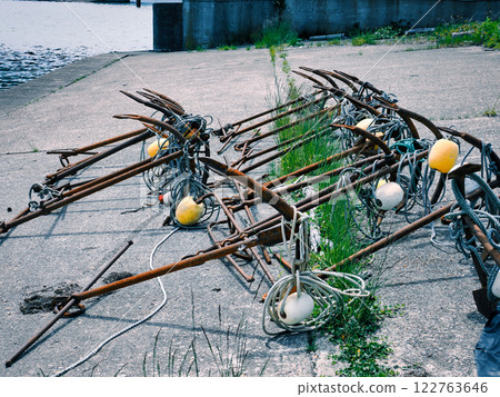 Rusty anchors lined up on the embankment of a fishing port 122763646