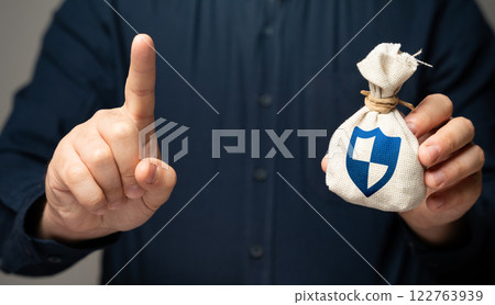 A man holds a bag with a shield symbolizing safety. Financial security, risk protection, investment safety, savings insurance, fraud prevention, and safeguarding wealth from economic uncertainty. 122763939