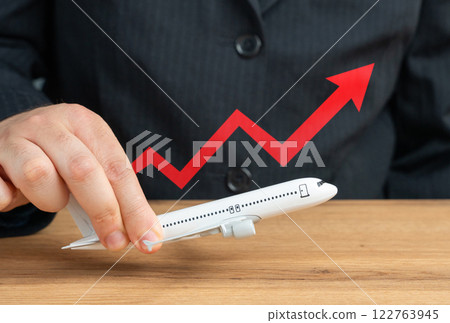 Passenger plane and red arrow pointing up. Concert of growth of passenger traffic, prices or expenses for flights. Growing aviation industry demand, expanding air travel Passenger plane and red arrow pointing up. Concert of growth of passenger traffic, prices or expenses for flights. Growing aviation industry demand, expanding air travel 122763945