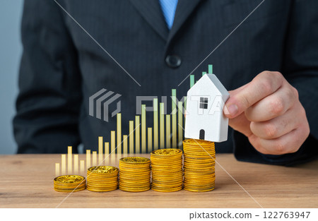 Businessman puts a house over the accumulated money. Earn for a house. Improve housing. Rent. Rent out. Mortgage planning, renting and leasing property, homeownership 122763947