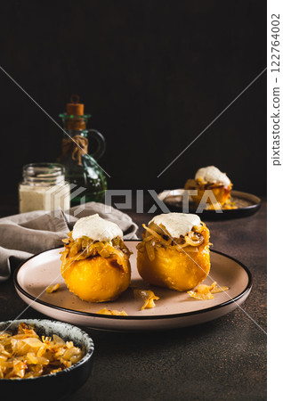 Baked potato with fried onions and ranch dressing on a plate on the table vertical view 122764002