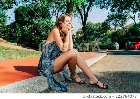 Bright and cheerful: a young woman on the phone in front of a stylish property, blending tech, joy 122764078