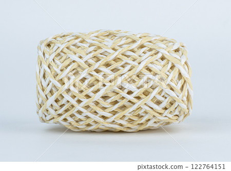 ball made of beige and white rope rests on a light background 122764151
