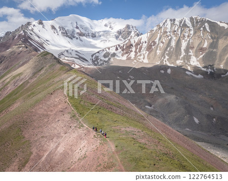 Aerial view on alpine landscape with hikers walking ridgeline up to snowy Pamir Mountains,Kyrgyzstan 122764513