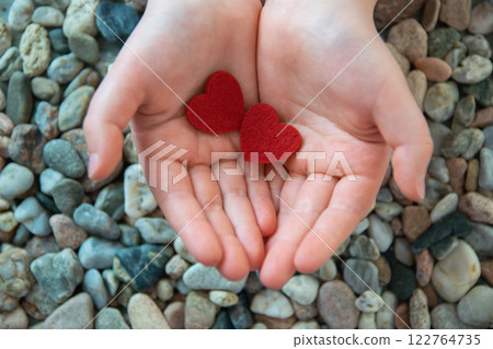 Two red hearts in child hands on the stones background. Concept of Valentine's day and romantic love. 122764735