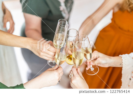 Birthday surprise party. Group of cheerful female friends celebrating personal success stories. Smiling girls toasting with glasses of champagne. 122765414
