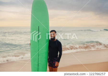 Surfer holding surf board on the beach at sunset. Happy man guy having fun doing extreme sport 122766257