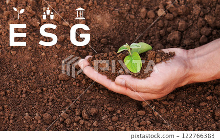 Environment social governance, a man is holding a small plant in his hand. The plant is in the hands and surrounded by earth. The concept of environmental problems, the concept of environmental 122766383