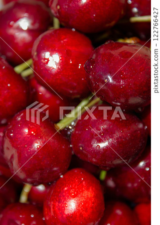 A bunch of red cherries are sitting on a table. The cherries are shiny and wet, and they are arranged in a pile A bunch of red cherries are sitting on a table. The cherries are shiny and wet, and they are arranged in a pile 122766427