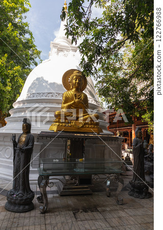 Sitting Buddha, golden statue placed in front of white pagoda Sitting Buddha, golden statue placed in front of white pagoda 122766988